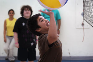 Boy hitting a beach ball in an indoor gym