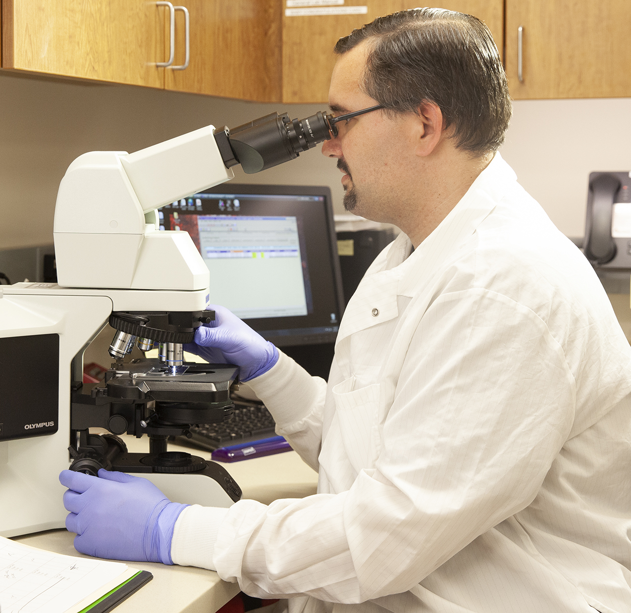 Lab technician looking through microscope.